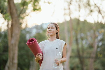 Young Asian woman practicing yoga in a quiet park, gracefully in a relaxed pose, relaxing and...