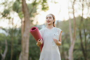 Young Asian woman practicing yoga in a quiet park, gracefully in a relaxed pose, relaxing and...