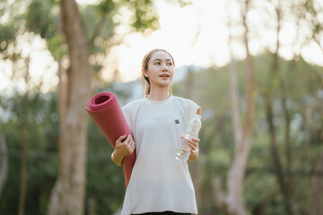Young Asian woman practicing yoga in a quiet park, gracefully in a relaxed pose, relaxing and...