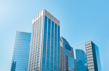 Four high-rise buildings with mirrored windows against a clear blue sky