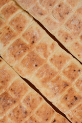 A close-up, top-down view of three flatbreads aligned horizontally, displaying their textured surface and characteristic grid pattern against a neutral background