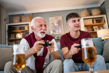 Grandfather and grandson playing video games and drinking beer at home