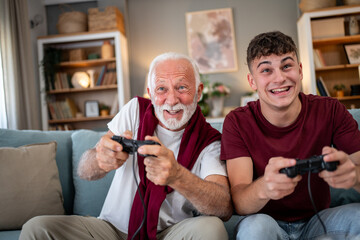 Grandfather and grandson playing videogames on sofa at home