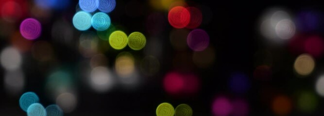 colorful moving bokeh lights isolated on blurred background banner, closeup of vibrant light decoration on black, overlay template 