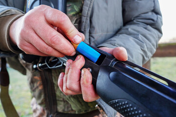 Shotgun in hunter hand. Hunter loads Cartridge (firearms) with shot into a double-barreled shotgun....