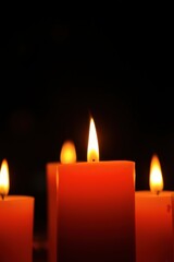 Burning Red Candles with Warm Glowing Flames Against a Dark Background