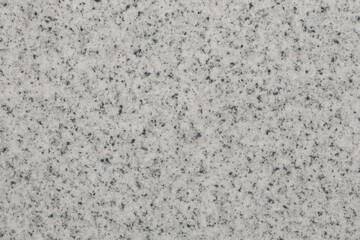 Close-up view of polished white granite, showcasing subtle textures and tiny black specks that create an elegant, natural pattern ideal for design and architecture