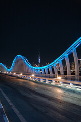 Obraz premium Meydan Bridge and street road or path way on highway with modern architecture buildings in Dubai Downtown at night, urban city at night, United Arab Emirates or UAE. 