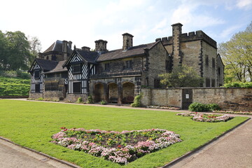 Shibden Hall in Halifax, a historic English manor set amidst beautiful gardens, with a delightful heart-shaped flower bed in the foreground. Calderdale, West Yorkshire, England, UK.