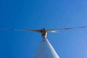 A lone wind turbine against a blue sky and white clouds. Green energy concept