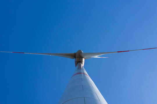 A lone wind turbine against a blue sky and white clouds. Green energy concept