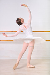 Graceful ballerina in white leotard performing in studio © TRAVELARIUM