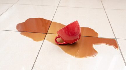 Spilled coffee, coffe puddle stain on tiled floor, messy leak with fallen cup, brown drink spillage