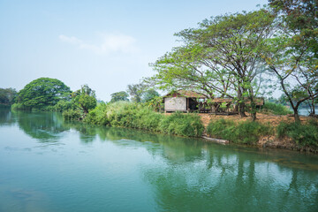 Obraz premium Views of Don Det, 4000 Islands,,a river flowing through a village and lush trees
