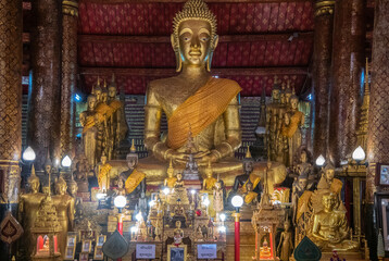 A Serene Buddha Statue is Surrounded by Beautiful Offerings in an Ornate Temple Structure, Luang Prabang, Laos