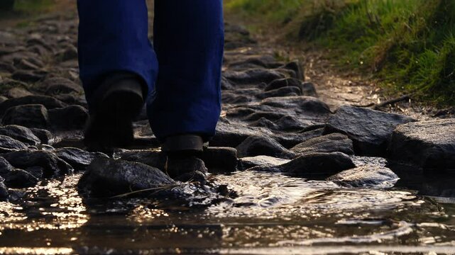 Woman walks over stream filled with stones and pebbles