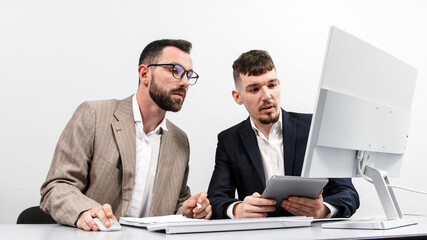Two business men are brainstorming in a bright office, working and analyzing data from a computer. The concept of successful business and teamwork. 