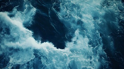 A deep blue ocean with white foam crashing against a rugged coastline
