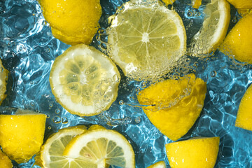 Juicy lemon background of halves and slices of fresh lemons in water.