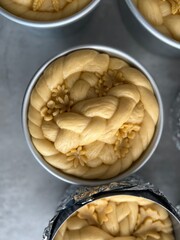 Unbaked traditional Ukrainian Easter bread with symbolic dough decoration in baking forms
