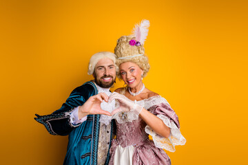 Elegant couple portraying royalty in vintage costumes with a vibrant yellow background