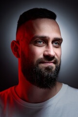 Studio portrait with colorful light of young handsome bearded man.