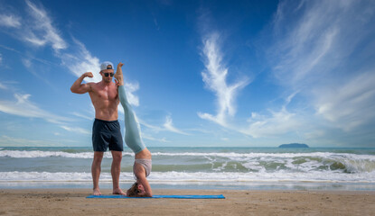 Sport man and woman exercise on beach at daytime