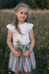 Happy girl walking in a summer field. A girl with a white flower in her hands. A joyful girl.