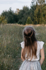Happy girl walking in a summer field. A girl with a white flower in her hands. A joyful girl.
