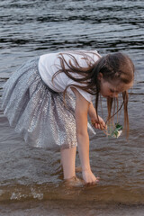 A girl in a white t-shirt walks on the sand next to the sea