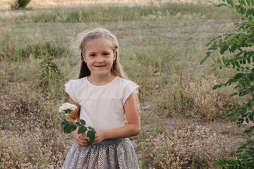 Happy girl walking in a summer field. A girl with a white flower in her hands. A joyful girl.