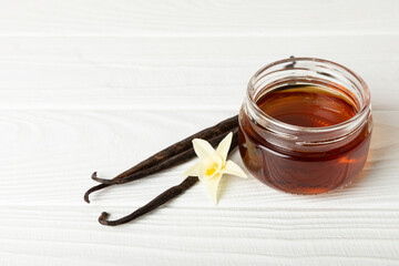Vanilla extract in glassware on a wooden table. Vanilla extract for baking and desserts. Aromatic Homemade Vanilla Extract. Close -up. Place for the text. Copy space.
