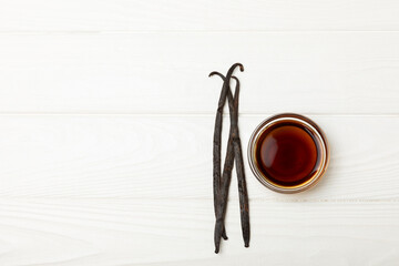 Vanilla extract in glassware on a wooden table. Vanilla extract for baking and desserts. Aromatic Homemade Vanilla Extract. Close -up. Place for the text. Copy space.