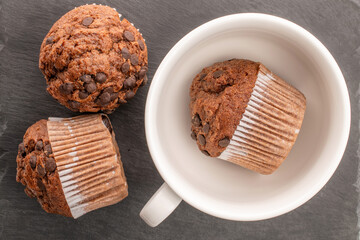 Chocolate muffins with coffee and kitchen utensils, close-up, top view.