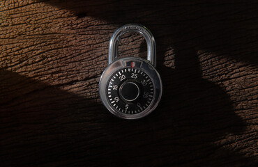 Combination padlock and master key with shadow on wood background
