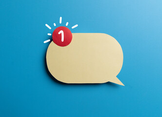 Yellow speech bubble with envelope and red notification badge on blue background. Concept of new message alert, email communication,