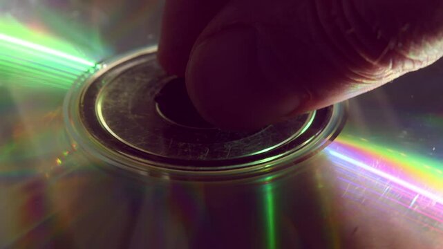 Person places double-sided CD into tray, but it spins briefly and stops due to read error, evoking raw 90s nostalgia and tech fragility in 4K