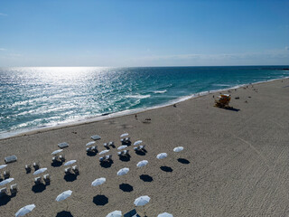 Sunbed on a sandy beach with ocean waves. Peaceful seaside retreat under the summer sun. Relaxing sun loungers facing the tranquil sea. Miami Beach paradise with stunning views. Coastal relaxation.
