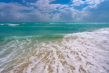 Turquoise sea water wave motion. Summer beach. Calm sea. Beauty sky and waves on beach. Beautiful foamy shoreline. Sea background. Blue ocean. Sandy ocean beach. Sea waves.