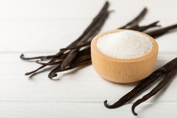 Fototapeta premium Aromatic vanilla sugar. Vanilla pods. Vanilla sticks, brown and white sugar in a bowl on a textured background. Vanilla flowers, spices and herbs for desserts and baking. Space for text. Copy space