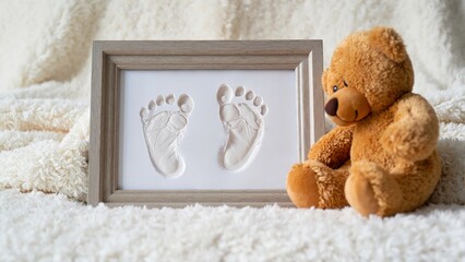 Cherished baby footprints beside cuddly teddy bear, treasured memories