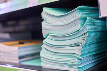 Examination papers stacked neatly in a classroom environment, ready for assessment. The green covers indicate they are standardized test materials, organized for student distribution.