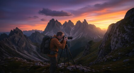 Photographer at sunset with mountain peaks.