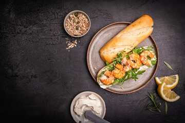 Healthy shrimp sandwiches for breakfast, snack, appetizers Toast with grilled prawns and whole grain bread with cream cheese and arugula on a dark background, top view