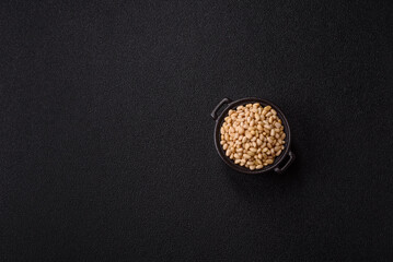 Peeled pine nuts in a bowl on a dark concrete background