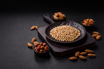 Peeled pine nuts in a bowl on a dark concrete background