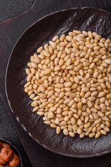 Peeled pine nuts in a bowl on a dark concrete background