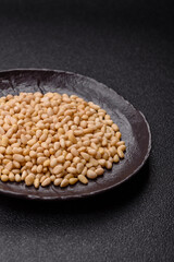 Peeled pine nuts in a bowl on a dark concrete background