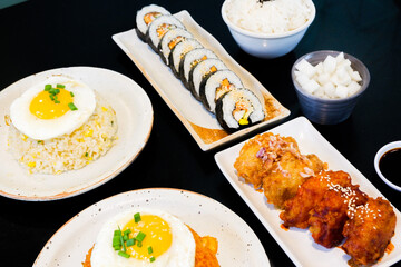 Korean foods served on a dining table,Gimbap,Fried chicken, radish,kimchi,spicy sauce with rice, seaweed,bibimbap,kimbap,Kimchi fried rice with fried egg and scallion sprinkle,copy space.