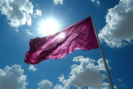 A deep crimson flag billows in a vibrant blue sky, punctuated by fluffy white clouds and the radiant sun